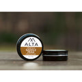 Alta Body Saddle Peak Premium Beard Balm in a 2oz black tin resting on a wooden surface. Natural cedar and leather scent.